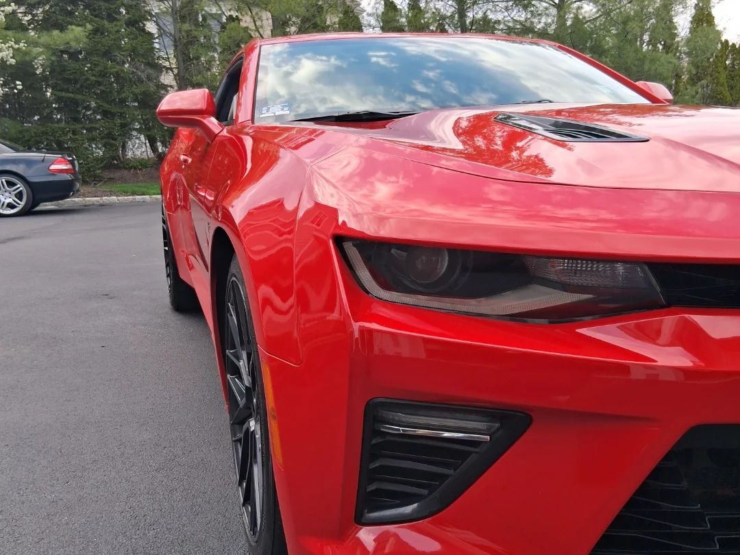 Close-up of glossy red Camaro SS paint and headlight after an exterior detail