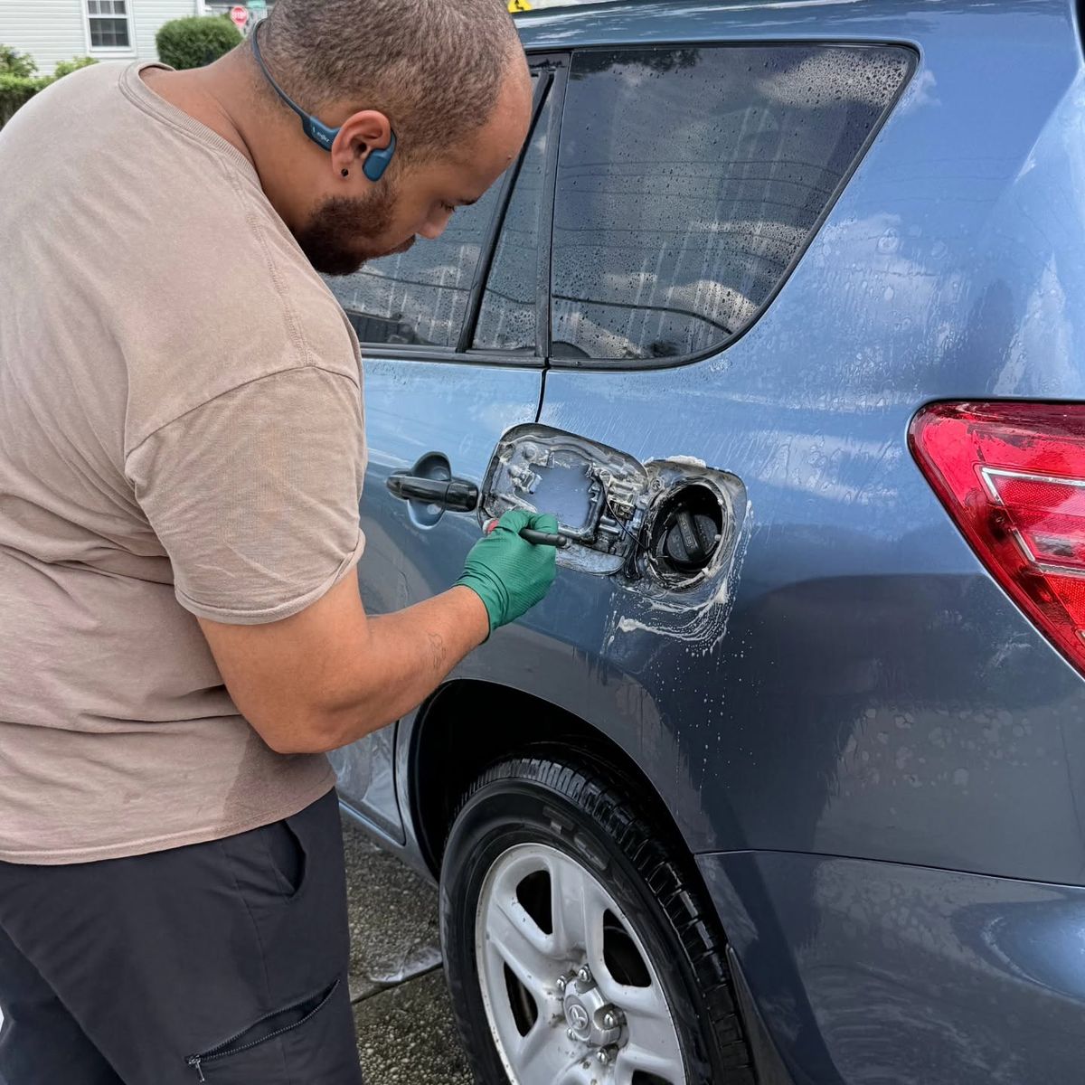 Patrick cleaning inside the fuel door of a blue Toyota RAV4 with a detailing brush