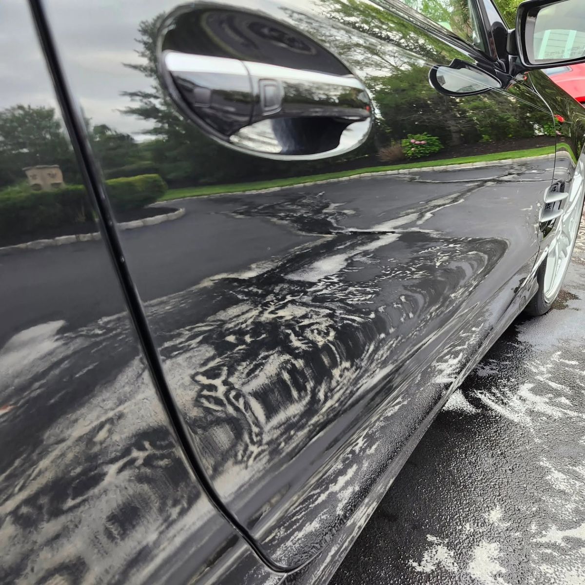 Black Mercedes-Benz SL door covered in foam during the pre-wash