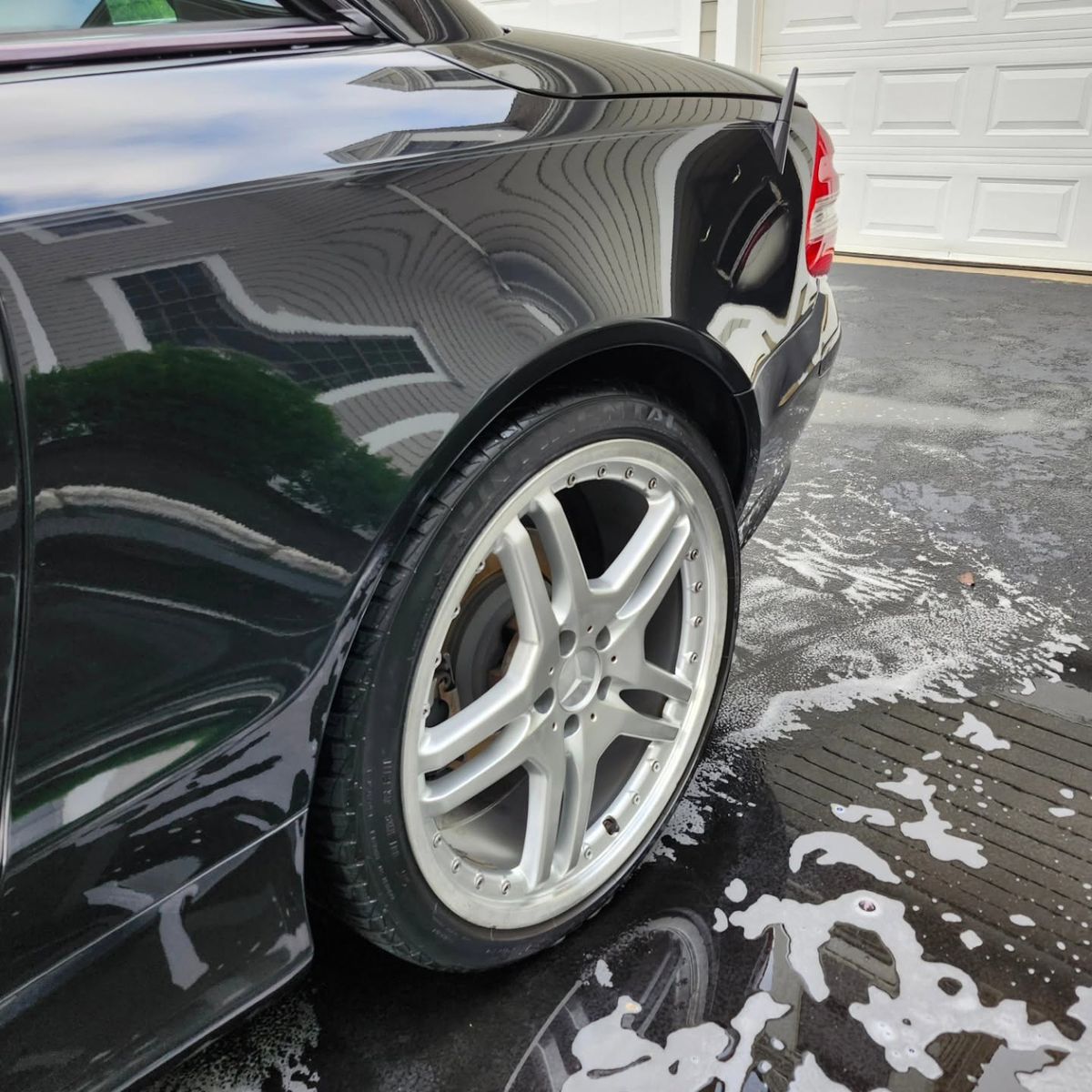 Glossy black Mercedes-Benz SL rear fender and clean silver wheel after a hand wash