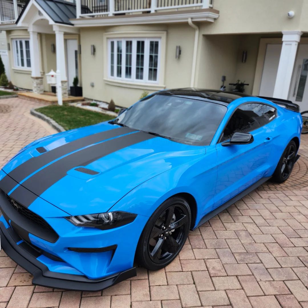 Bright blue Ford Mustang with black stripes, freshly detailed in a Long Island driveway