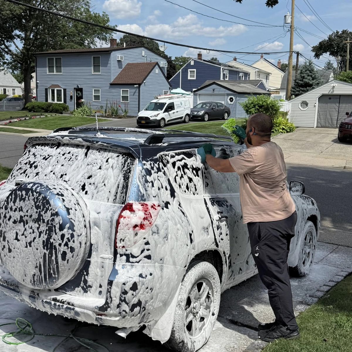 Patrick foam washing a blue Toyota RAV4 in a driveway
